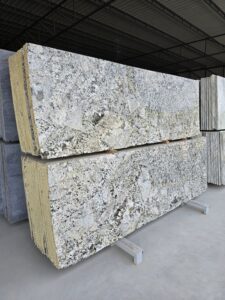 Angled view of Alaska White polished granite slabs highlighting the layered cuts, reflective polished finish, and striking contrast of white crystal patterns with dark grey veining. Perfect for kitchen countertops, wall cladding, and modern home design projects.