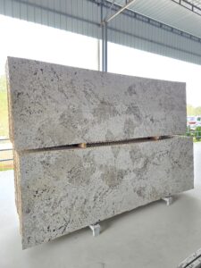 “Front display of Imperial Alaska White polished granite slabs featuring elegant white and grey veining, subtle crystal formations, and smooth polished surface. Perfect natural stone for kitchen countertops, wall cladding, and modern interior design applications.”