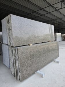 Angled side view of Apple Green Leather Finish Granite slabs stacked vertically, showing their unique leather-textured surface, earthy green tones, and consistent mineral composition. Suitable for kitchen countertops, wall cladding, and architectural stone design.