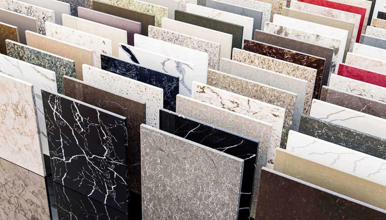 An entire landscape of polished stone panels rises in quiet formation, each slab carrying its own rhythm of veins, flecks, and mineral hues. From deep noir surfaces that feel almost cosmic to soft creams, earthy browns, bold marbles, and shimmering quartz patterns, this collection showcases the full vocabulary of modern surfaces. Here, designers and homeowners wander through possibilities, choosing the texture and tone that will anchor their spaces with character and permanence